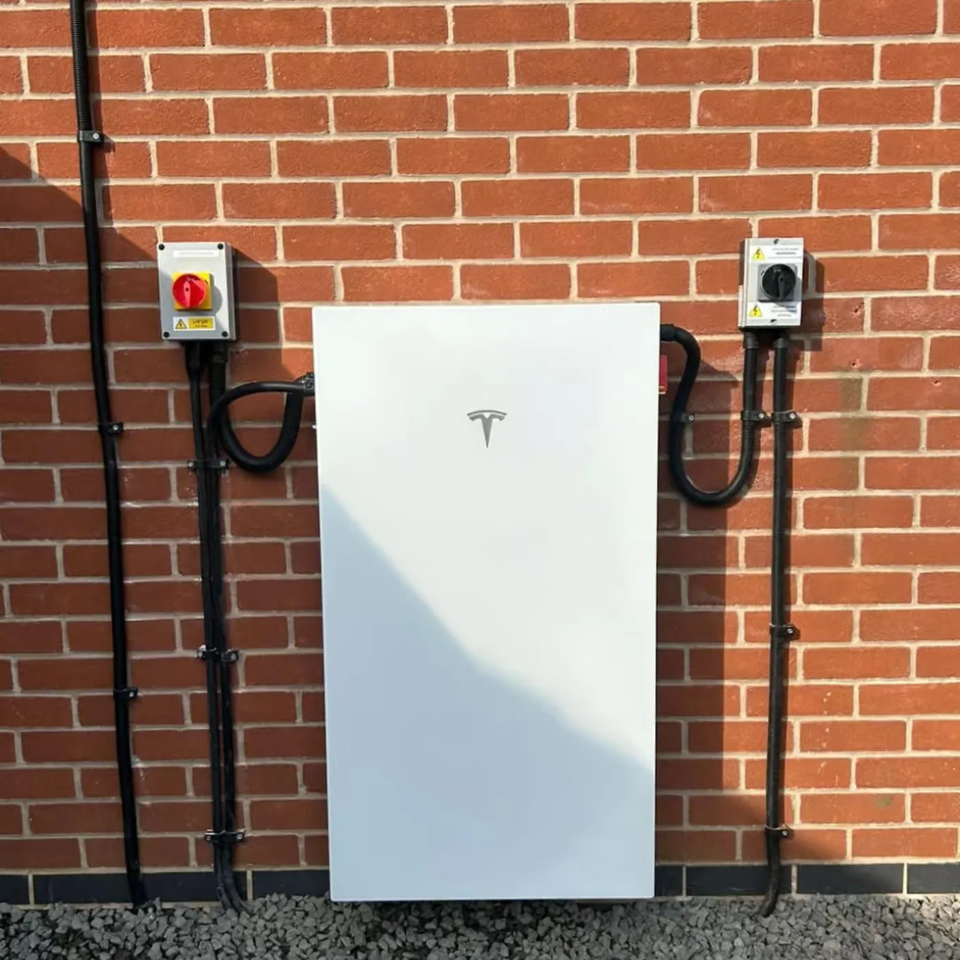 Tesla Powerwall 3 installed on a brick wall with isolators and conduit
